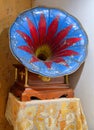 Ancient gramophone with red lily on nightstand