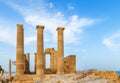 Ancient Greek pillars at Lindos acropolis with blue cloudy sky in the background Royalty Free Stock Photo