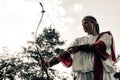 Ancient greek woman archer aims and shoots from bow on meadow Royalty Free Stock Photo