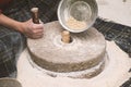 The ancient hand mill or quern stone, grinds the grain into flour.