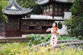 Ancient historic Asian Chinese woman artist traditional chi-pao cheongsam in a garden play musical instruments violin on bridge