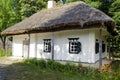 An ancient house with clay whitewashed walls, thatched roof and rounded windows in rectangular black frames Royalty Free Stock Photo