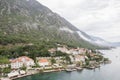 Ancient houses with red roofs at the foot of the mountains on the shores of the Bay of Kotor. Dobrota, Montenegro. Drone