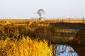 Ancient isolated wind turbine in dutch rural landscape with small stream and crop field near traditional village Zaanse Schans,