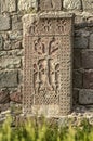 Khachkar standing at the old wall in a park located around the Geghard monastery located in the mountains of Armenia Royalty Free Stock Photo