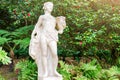 Ancient marble women statue in the park. Sculptured figure of young woman on blooming garden background Royalty Free Stock Photo