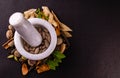 Ancient medicine systems concept. Top view of ayurvedic tablets in a mortar and different spices, green leaves on black background