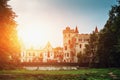 Ancient Medieval Castle or Stronghold with turrets and towers among green forest at sunset light