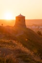 Ancient medieval lookout tower lit by golden light on a hill at dawn