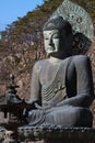 A ancient metal carving of sitting peace buddha in front of tree mountain and painted with green color at large historical Royalty Free Stock Photo