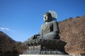 A ancient metal carving of sitting peace buddha in front of tree mountain and painted with green color at large historical Royalty Free Stock Photo