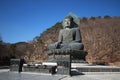 A ancient metal carving of sitting peace buddha in front of tree mountain and painted with green color at large historical Royalty Free Stock Photo