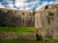 Ancient military fortress stone wall and round tower with embrasure under blue sky view from the fort territory Royalty Free Stock Photo