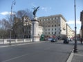 Ancient and modern buildings, statues from the Roman Empire period, street and cars in the city of Rome