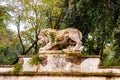 Ancient mossy overgrown lion stone sculpture statue in Borghese park on the way to the Villa Borghese