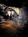 Ancient mountain cave with stalactites, stalagmites, long underground river in white and red stones with petroglyph