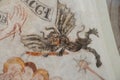 An ancient mural of a black devil with bat wings hacking at people