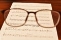 Ancient Musical Manuscript, Abstract Music Sheet and eye glasses on wooden table Royalty Free Stock Photo