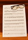 Ancient Musical Manuscript, Abstract Music Sheet and eye glasses on wooden table. Royalty Free Stock Photo