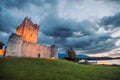 Ancient old Fortress Ross Castle with a lake, green grass and orange clouds. Killarney national park, co Kerry, Ireland