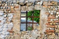 Ancient old square window open but with bars on old stone wall looking into a garden. Royalty Free Stock Photo
