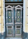 Ancient old wooden door with peeling paint. Ancient exterior carved door with columns and capitals on the facade of the building. Royalty Free Stock Photo