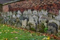 Ancient Overgrown Tombstones And Graves Placed Relocated Against Brick Wall At Churchyard Garden On Autumn Morning