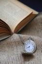 ancient pocket watch in front of an old book on a piece of cloth