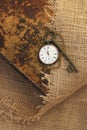 Ancient pocket watch and key on old folio half-covered with old sackcloth. Time passing concept. Knowledge eternity concept Royalty Free Stock Photo