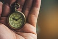 An ancient pocket watch placed on hand.