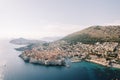 Ancient port of Dubrovnik with castle walls on the seashore at the foot of the mountains. Croatia. Drone