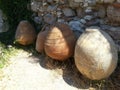 Ancient pottery vessels upside down on ground against stony wall