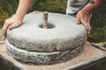 The ancient quern stone hand mill with grain. The man grinds the grain into flour with the help of a millstone. Men`s Royalty Free Stock Photo