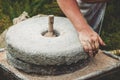 The ancient quern stone hand mill with grain. The man grinds the grain into flour with the help of a millstone. Men`s Royalty Free Stock Photo