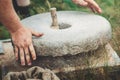 The ancient quern stone hand mill with grain. The man grinds the grain into flour with the help of a millstone. Men`s Royalty Free Stock Photo