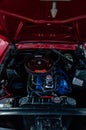 Ancient red Ford Mustang with its hood up and engine exposed, showing its impressive power