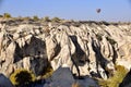 Ancient Rock Dwellings in Goreme, Cappadcia, Turkey, with hot air balloon above.