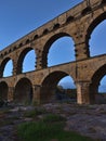 Ancient Roman aqueduct Pont du Gard with stone pillars above Gardon river after sunset near Vers-Pont-du-Gard, Occitanie, France. Royalty Free Stock Photo