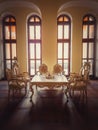 Ancient royalty dining room, medieval furniture style with golden ornate chairs and table near the arched windows. Luxury hosting Royalty Free Stock Photo