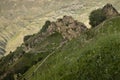 Ancient ruin of stone impregnable city on peak of mountain with road in highlands in Dagestan with landscape - green slopes, deep.