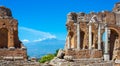 View over the ancient ruins of the Roman-Greek theatre in Taormina to the smoking volcano Etna, Sicily, Italy