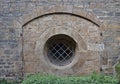 Ancient sandstone wall with arch and barred round window Royalty Free Stock Photo