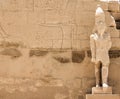 Ancient sculpture of Pharaoh on the background of a stone wall with Egyptian hieroglyphs and thematic drawings Royalty Free Stock Photo