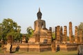 Ancient sculpture of a seated Buddha at the ruins of the temple Wat Chana Songkhram in the rays of the setting sun. The view from Royalty Free Stock Photo