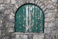 Ancient semicircular window with nailed green wooden shutters.