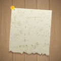 Ancient sheet of torn paper pinned with a pin. Wooden background Royalty Free Stock Photo