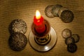 Ancient silver coins and burning candle Royalty Free Stock Photo