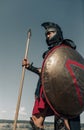 Ancient Spartan warrior in battle dress stands with shield and spear