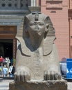 Red granite sphinx of Thutmose III in front of the Museum of Egyptian Antiquities in Cairo, with tourists.