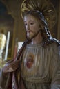 Ancient statue of Jesus Christ the Good Shepherd with hole in his hand pointing at his sacred heart and aureole - Biblical Royalty Free Stock Photo
